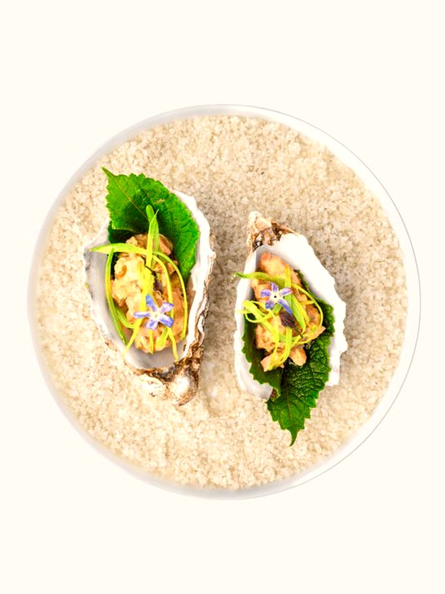 Huîtres dressées sur lit de sable, zestes et herbes